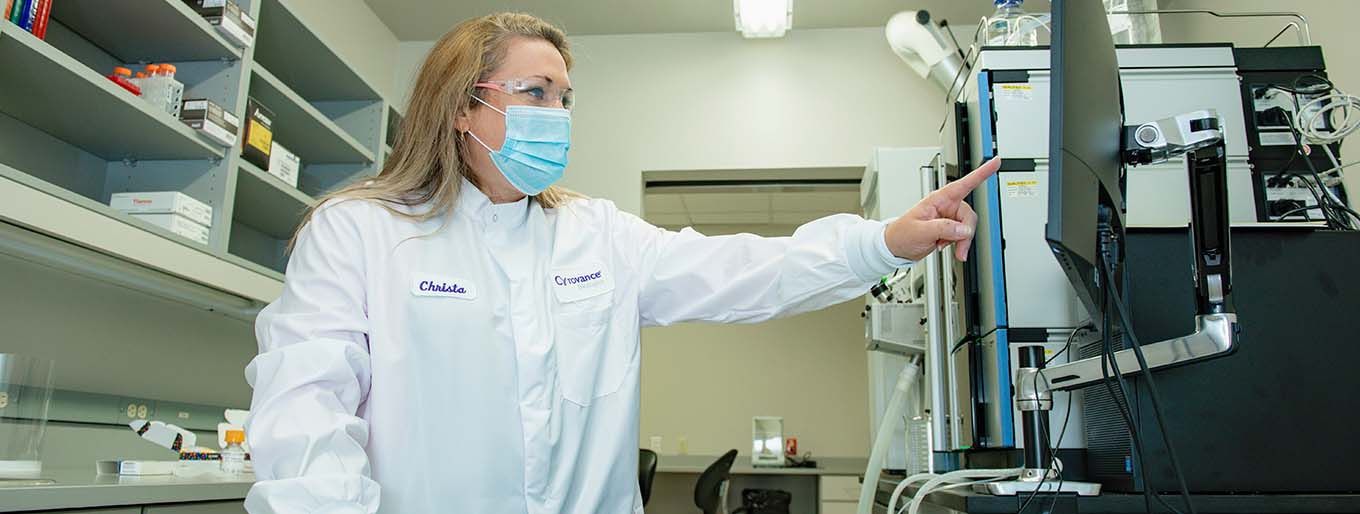 A female Cytovance microbial analytical methods development expert working on a mass spec.